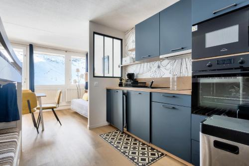 - une cuisine avec des armoires bleues et une table dans une pièce dans l'établissement Résidence Le Tourmalet - maeva Home - Studio au pied des pistes 4 personnes - Prestige - super Home MAE-9931, à La Mongie