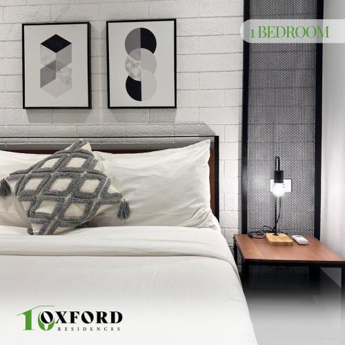 a bedroom with a bed and a nightstand and framed pictures at 10 Oxford Residences in Quezon City