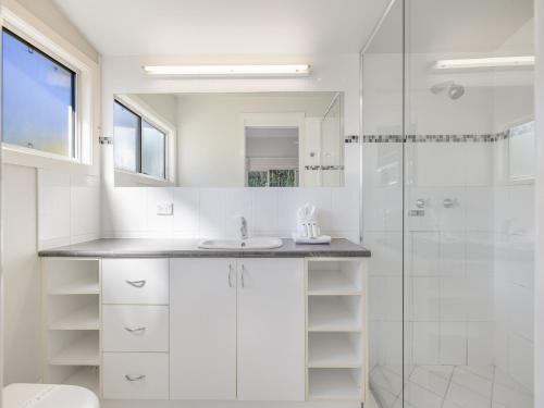 a white bathroom with a sink and a shower at Maroochy 4 Bedroom Family Beachhouse in Maroochydore