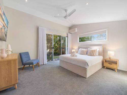 a bedroom with a white bed and a blue chair at Maroochy 4 Bedroom Family Beachhouse in Maroochydore