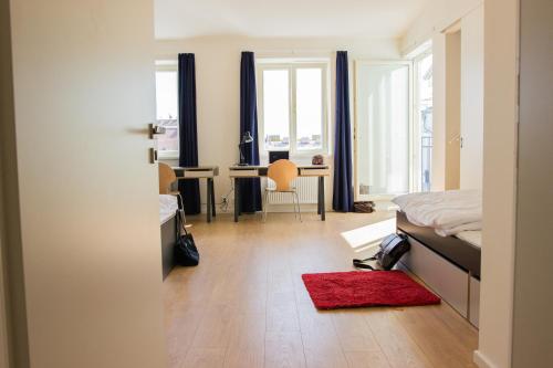プラハにあるBelgicka Executive Apartmentsのベッドルーム1室(ベッド1台、赤いラグ付きのデスク付)
