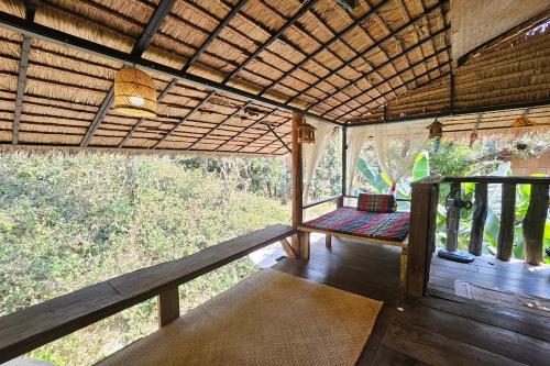 a porch of a house with a bench in it at Mae Mae Home in Ban Tham