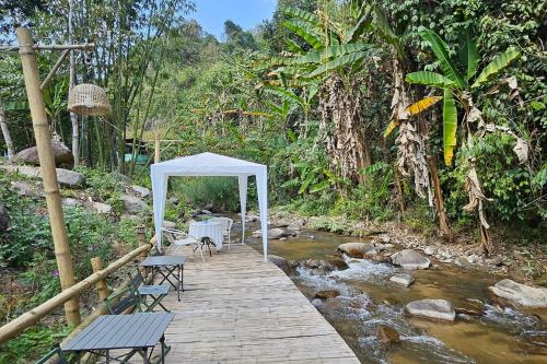 a wooden walkway with a tent and chairs on a river at Mae Mae Home in Ban Tham