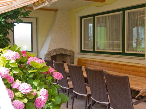 a patio with chairs and a table and flowers at Haus am Wald in Strobl