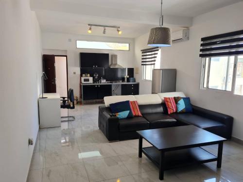 a living room with a black couch and a table at Cool Flat Cidade - Airport in Luanda