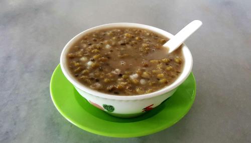 a cup of soup on a green plate on a table at Hin Loi Guesthouse in Kota Kinabalu