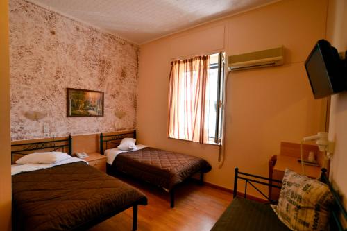 a small room with two beds and a window at Electra Hotel Piraeus in Piraeus