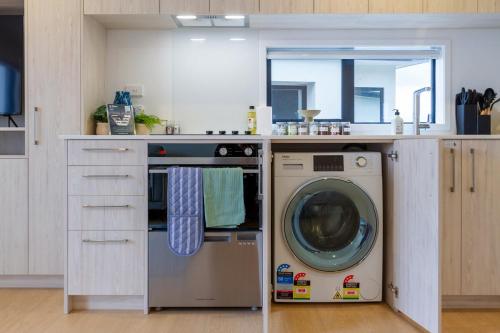 a kitchen with a washing machine under a counter at City Haven 1BR Near Ara Institute & CBD in Christchurch