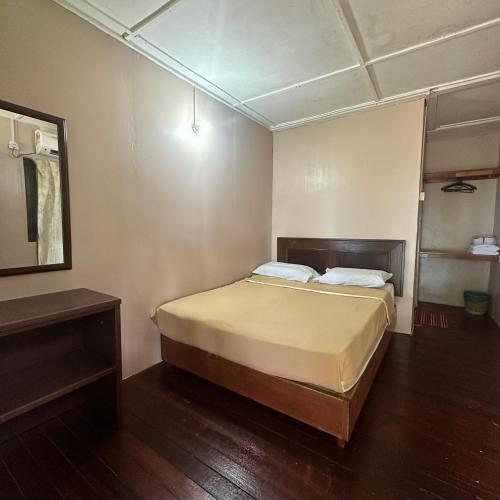 a small bedroom with a bed and a mirror at Johans Chalet in Tioman Island