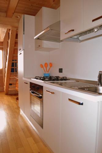 a kitchen with white cabinets and a stove top oven at Albergo Rendola in Asiago