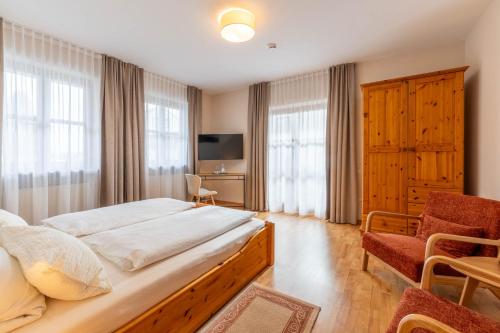 a bedroom with a bed and a chair and a television at Apartments Bauer in Grafing