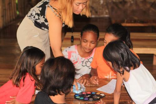a group of children standing around a table playing with dominoes at Villa-Atlas Guest House in Malapascua Island
