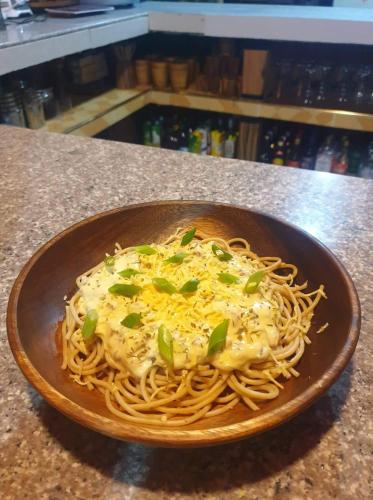 a bowl of spaghetti with cheese and greens on a counter at Villa-Atlas Guest House in Malapascua Island