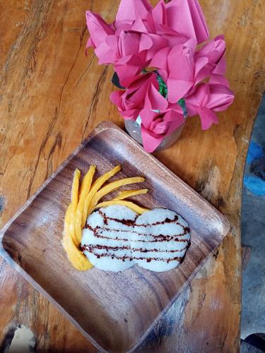 a cutting board with meat and fries on a table with flowers at Villa-Atlas Guest House in Malapascua Island