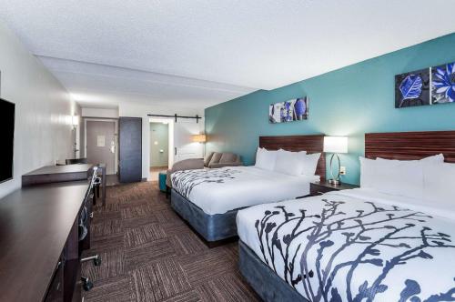 a hotel room with two beds and a flat screen tv at Sleep Inn & Suites Rehoboth Beach in Rehoboth Beach