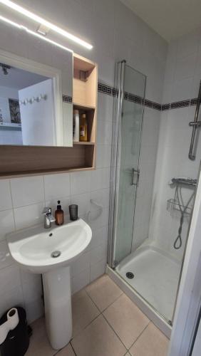une salle de bain blanche avec un lavabo et une douche dans l'établissement Maison plein centre ville à 100 m de la plage, à Saint-Georges-de-Didonne