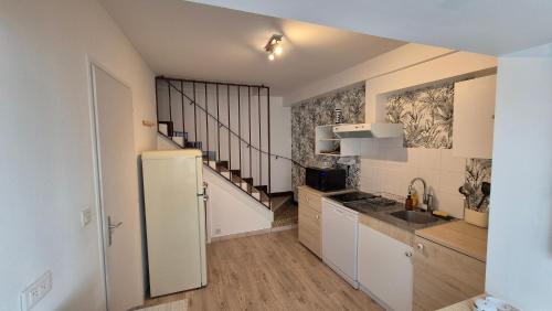 une cuisine avec un réfrigérateur blanc et un escalier dans l'établissement Maison plein centre ville à 100 m de la plage, à Saint-Georges-de-Didonne