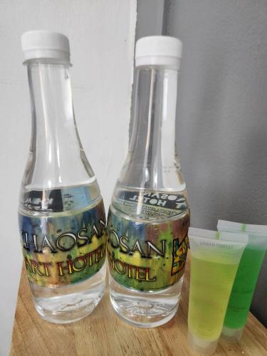 two bottles of water on a table with a drink at Khaosan Art Hotel in Bangkok