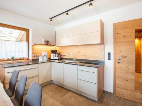 a kitchen with white cabinets and a sink and chairs at Chalet in Zell am Ziller near Ski Lift in Gerlosberg