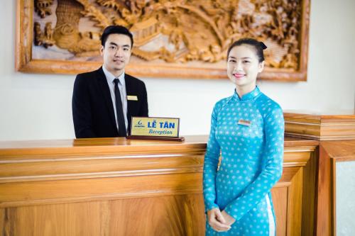 a man and a woman standing in front of a desk at Lam Giang Hotel in Vinh