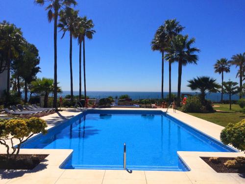 een zwembad met palmbomen op de achtergrond bij La Perla de Marakech in Estepona
