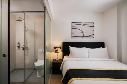 a bedroom with a bed and a glass shower at BRYQS Hotel in Kuala Lumpur