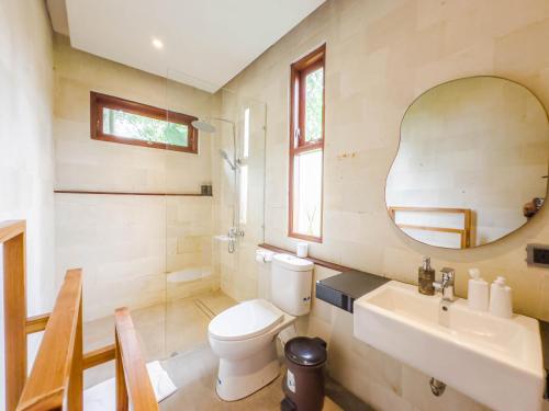 a bathroom with a toilet and a sink and a mirror at Ubud Shanti Rice Field House By Supala in Ubud
