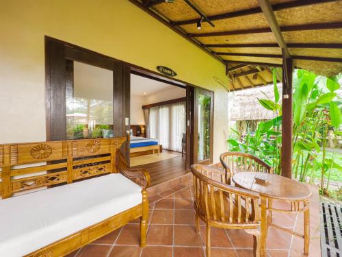 a porch with a bench and a table and chairs at Ubud Shanti Rice Field House By Supala in Ubud