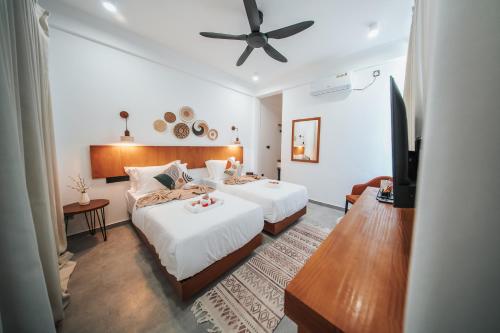 a bedroom with two beds and a ceiling fan at Belena Maldives in Thoddoo