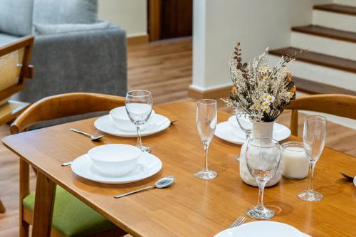 a wooden table with plates and wine glasses on it at La Ferringhi Villa - Balinese Collection, by ALV in Batu Ferringhi