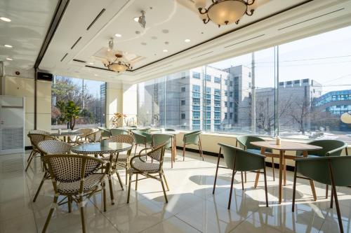 a restaurant with tables and chairs and a large window at Hotel Kabo Pyeongtaek in Pyeongtaek