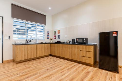 a kitchen with wooden cabinets and a black refrigerator at La Ferringhi Villa - Balinese Collection, by ALV in Batu Ferringhi