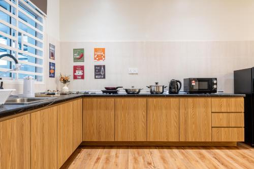 a kitchen with wooden cabinets and a microwave at La Ferringhi Villa - Balinese Collection, by ALV in Batu Ferringhi