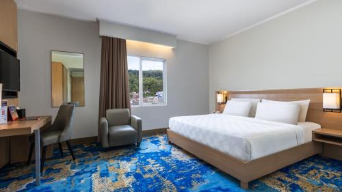 a hotel room with a bed and a desk and a computer at Swiss-Belhotel Manokwari in Manokwari