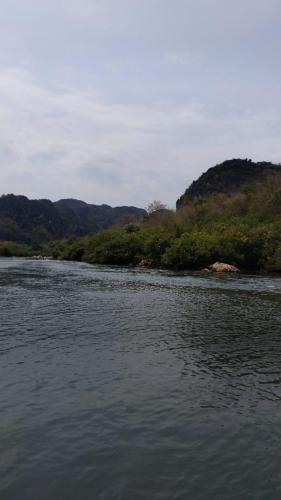 a body of water with trees in the background at Naughty Boy Hostel Thakhek in Thakhek