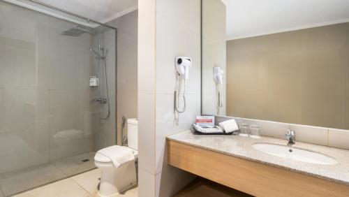 a bathroom with a sink and a shower and a phone at Swiss-Belhotel Manokwari in Manokwari