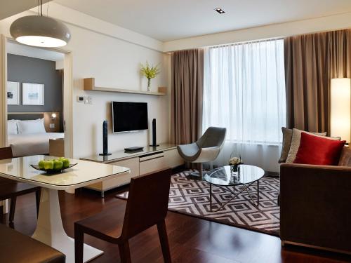 a hotel room with a desk and a living room at Pan Pacific Hanoi in Hanoi