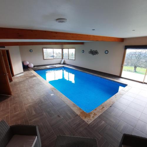 a large indoor swimming pool with blue water at Magnifique villa avec piscine intérieure in Saint-Pois