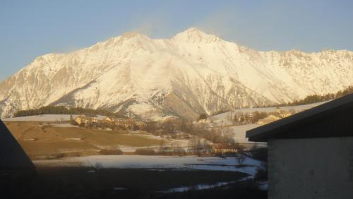 a snow covered mountain in front of a house at Hôtel l'Équipe in Le Sauze