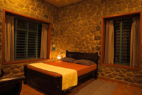 a bedroom with a bed in a stone wall at Fifth Estate in Vagamon