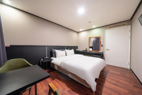 a bedroom with a bed and a table and a door at Hotel Kabo Pyeongtaek in Pyeongtaek