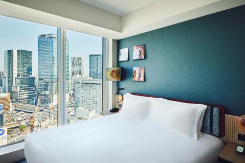 a bedroom with a large white bed and a large window at Hotel Indigo Tokyo Shibuya in Tokyo
