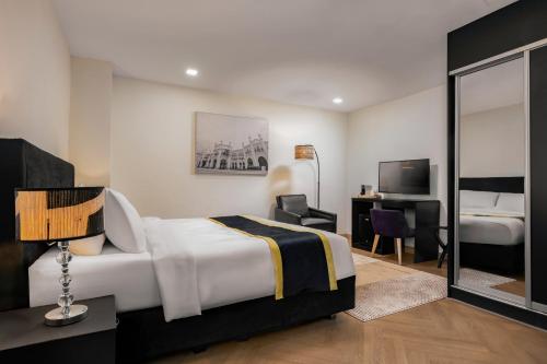 a bedroom with a bed and a desk and a television at BRYQS Hotel KL Sentral in Kuala Lumpur
