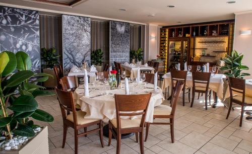 a restaurant with white tables and chairs and plants at Hotel Marina in Izola