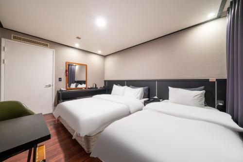 two beds in a hotel room with white sheets at Hotel Kabo Pyeongtaek in Pyeongtaek