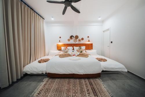 a bedroom with a large bed with a ceiling fan at Belena Maldives in Thoddoo