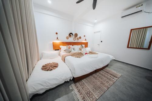 two beds in a room with white walls at Belena Maldives in Thoddoo
