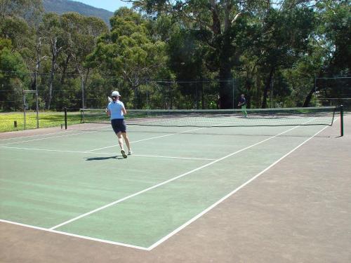 a woman is playing tennis on a tennis court at Pinnacle Holiday Lodge in Halls Gap