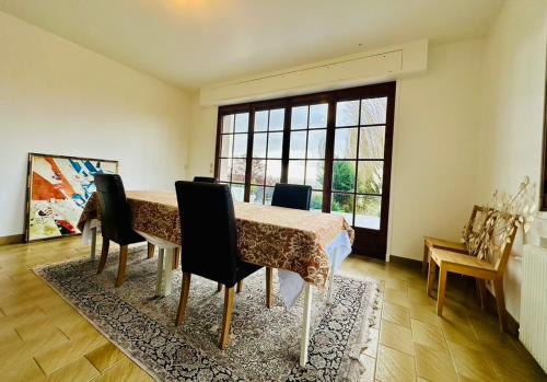 une pièce avec une table et des chaises et une grande fenêtre dans l'établissement Grande Maison dans la nature et le calme, à Juziers