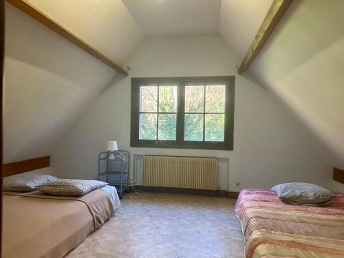 une chambre mansardée avec deux lits et une fenêtre dans l'établissement Grande Maison dans la nature et le calme, à Juziers